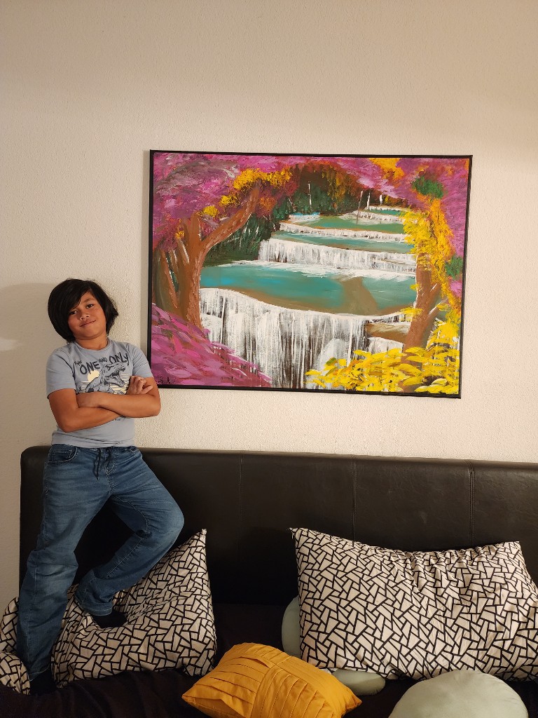 Shay standing beside his waterfall painting
